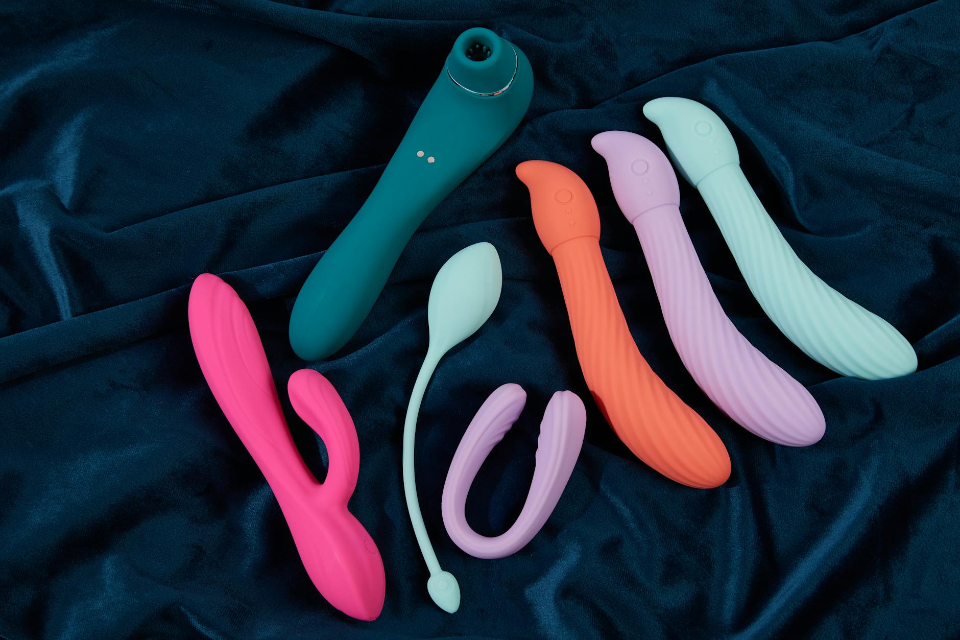 Woman holding vibrators, contemplating her body and pleasure after relational trauma