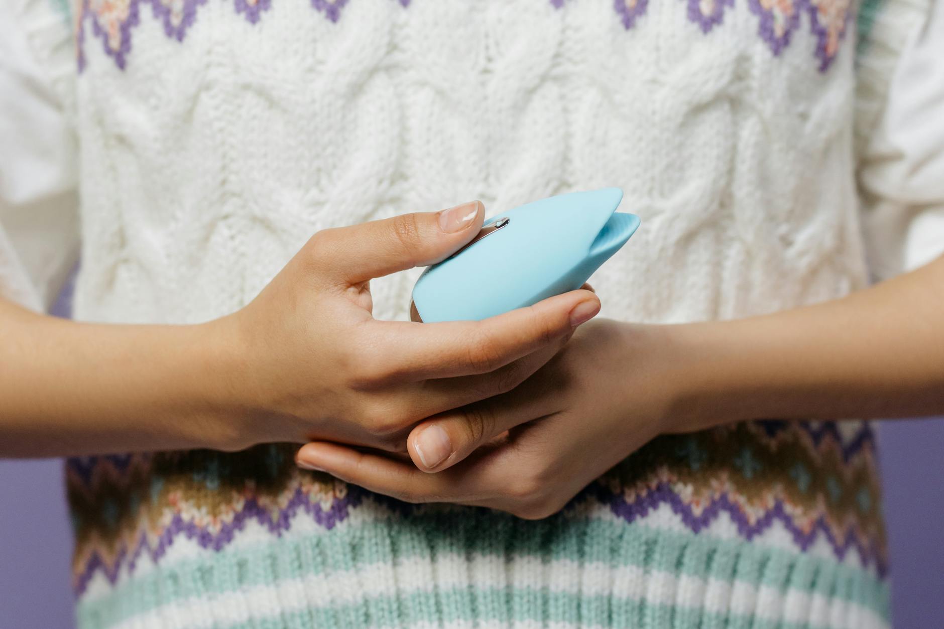 A couple standing together indoors, holding a blue vibrator and smiling, symbolizing shared intimacy and communication.